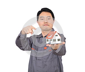 Young Chinese worker in overalls holding a small house model
