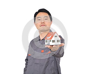 Young Chinese worker in overalls holding a small house model