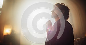 Young Christian Man Sits Piously in Majestic Church, with Folded Hands He Seeks Guidance From Faith