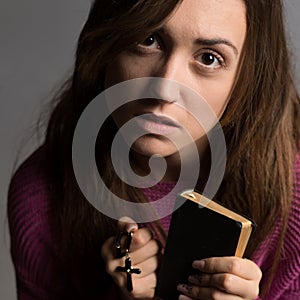 Young christian woman holding cross and psalm book