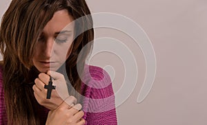 Young christian woman holding cross and psalm book