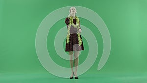 A young Christmas woman calls to the viewer on the green screen