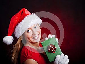 Young christmas woman holding present over dark