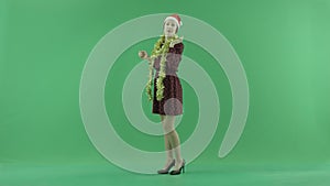 A young Christmas woman sends air kisses to the viewer on the green screen