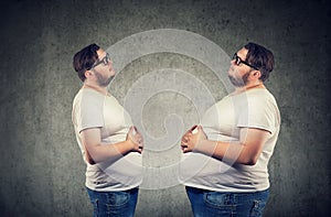 Young chubby man looking at fat himself feeling bloated.