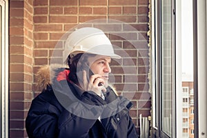 Young civil engineer is having trouble over the phone against brick background. Soft focus, toned. photo