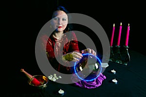 A young clairvoyant and fortuneteller divines over a mirror ball in a magic salon on a black background.