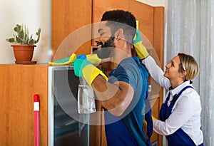 Young cleaners cleaning and dusting in ordinary house