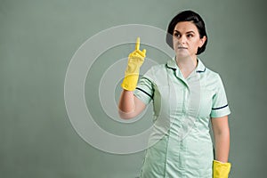 Young cleaning woman wearing a green shirt and yellow gloves get an idea