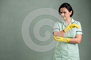 Young cleaning woman wearing a green shirt and yellow gloves has elbow pain