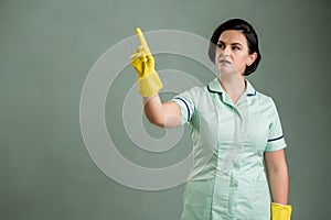 Young cleaning woman wearing a green shirt and yellow gloves presses a virtual button