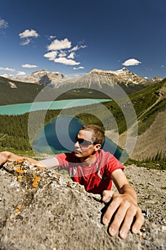 Young climber reaches for handhold in mountains