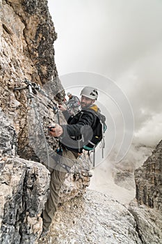 Young climbers on a steep and exposed rock face climbing a Via Ferrata