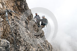 Young climbers on a steep and exposed rock face climbing a Via Ferrata