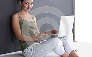 A young colledge girl sitting on the floor with a laptop