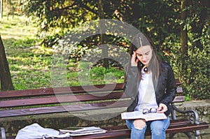 Young college or school girl feeling sick with strong headache pain or migraine attack while she sitting on the bench in the park