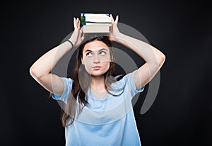 Young college student holding stack of books on head