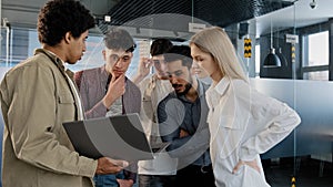 Young company employee explains development strategy tells new ideas showing work plan on laptop to smiling diverse