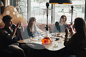 Young company is having fun and eating in bar. smoking a hookah, communicating in an oriental restaurant.