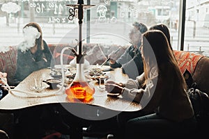 Young company is having fun and eating in bar. smoking a hookah, communicating in an oriental restaurant.