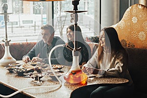 Young company is having fun and eating in bar. smoking a hookah, communicating in an oriental restaurant.