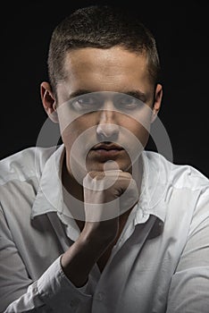 Young composed man with his fist to chin thinking