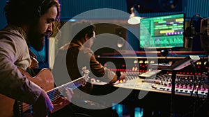 Young composer songwriter recording his guitar tunes in professional studio