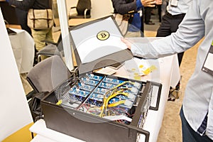 Young computer engineer showing the paper with the sign of bitcoin at cryptocurrency mining farm