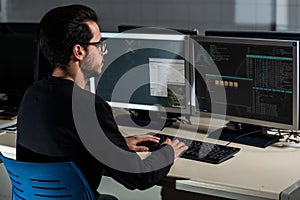 Young computer science student developing with his computer on a Linux System over double screen system photo