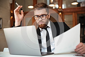 Young concentrated bearded businessman in formalwear looking at