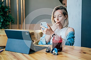 Young concentrated businesswoman working on laptop and mobile phone