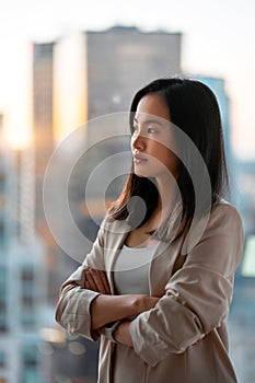Young confident Asian business woman executive looking at window thinking.