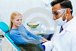 Young confident asian male dentist checking teeth x ray of patient. Dental clinic concept.