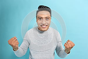 Young confident asian man in eyeglasses joyfully showing yes gesture on camera over blue background