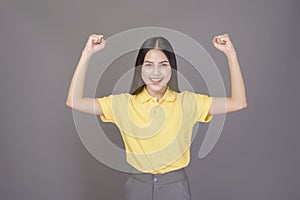 Young confident beautiful woman wearing yellow shirt is on grey background studio