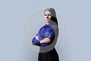 Young confident business woman looking at camera on grey background