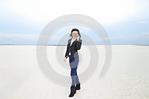 Young confident businesswoman standing on snow in monophonic background, wearing glasses.