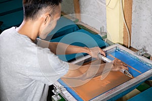 Young confident, experienced male working with squeegee on a small factory