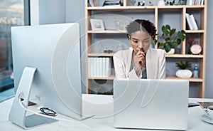 Young confident, focused and thinking businesswoman sitting alone in an office and browsing the internet on a computer