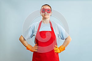 Young confident housewife in cleaning superhero costume on blue background