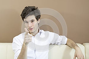 Young confident man dressed elegantly is sitting on the couch