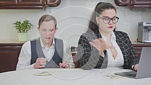 Young confident plump woman at the table working with laptop. A timid young man touches her shoulder and extends hand