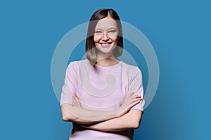 Young confident woman with crossed arms on blue background