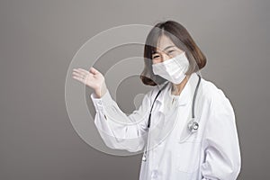 Young confident woman doctor is wearing surgical mask over grey background studio