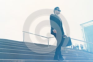 Young confidental businessman wearing suit and running fast downstairs. Horizontal outdoors shot