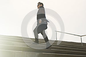 Young confidental businessman wearing suit and running fast upstairs. Horizontal outdoors shot