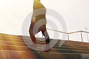 Young confidental businessman wearing suit and running fast upstairs. Horizontal outdoors shot.Sunny effect.