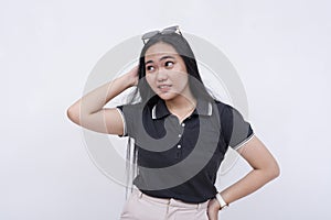 A young confused asian woman on her wits end. Scratching her head, unsure what to do. Isolated on a white background