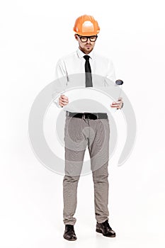 Young construction engineer in orange helmet studying layout plan on white background