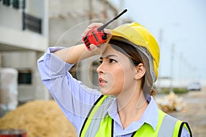 Young construction engineer woman wearing safety helmet wipes sweat on her face. Tired heat and hot at building construction site